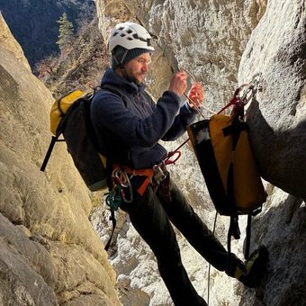Un guide de canyoning à Orpierre installe une corde au sommet d'une cascade.webp